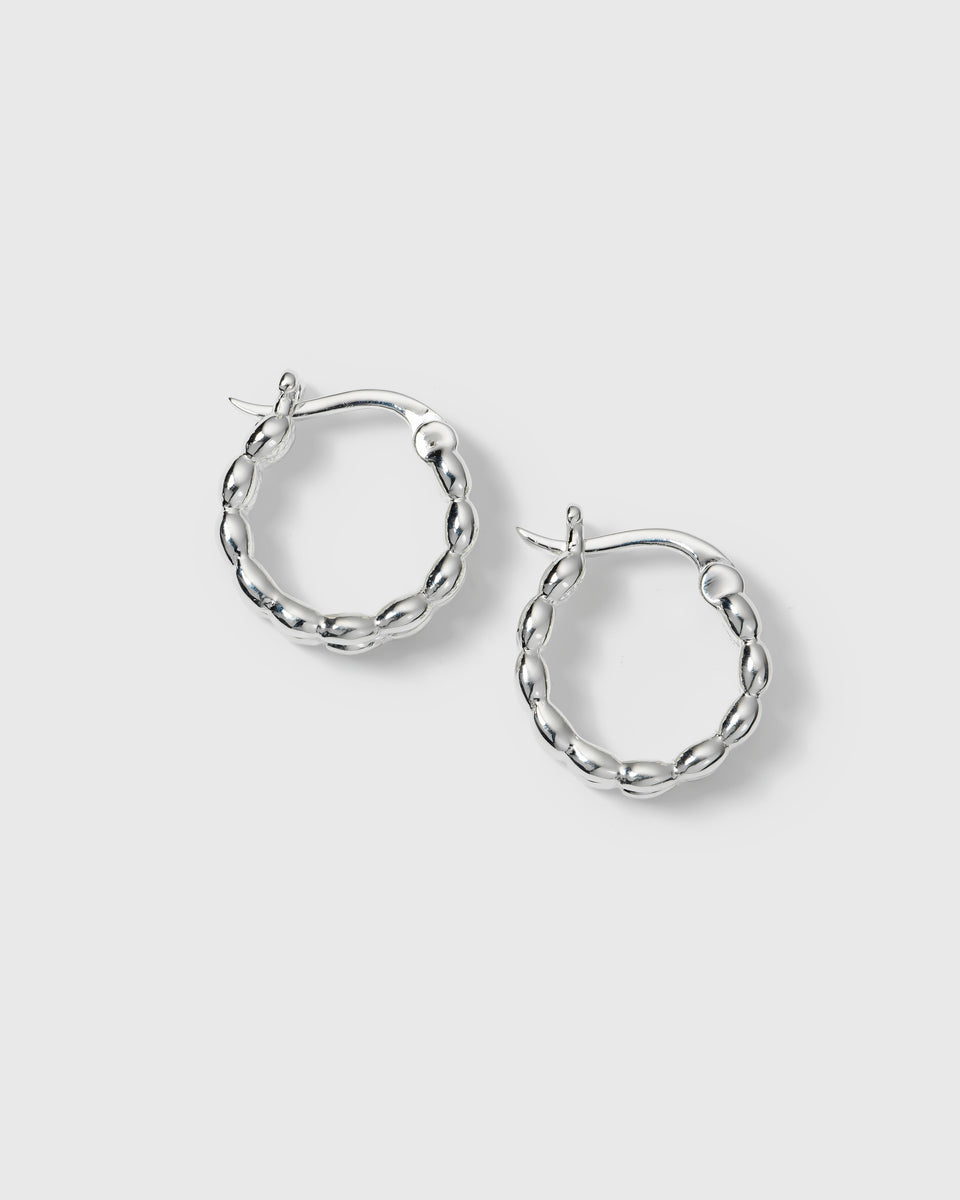 A product shot of the silver Lunetta Earrings, showcasing their unique hoop design formed by a pattern of small ovals.