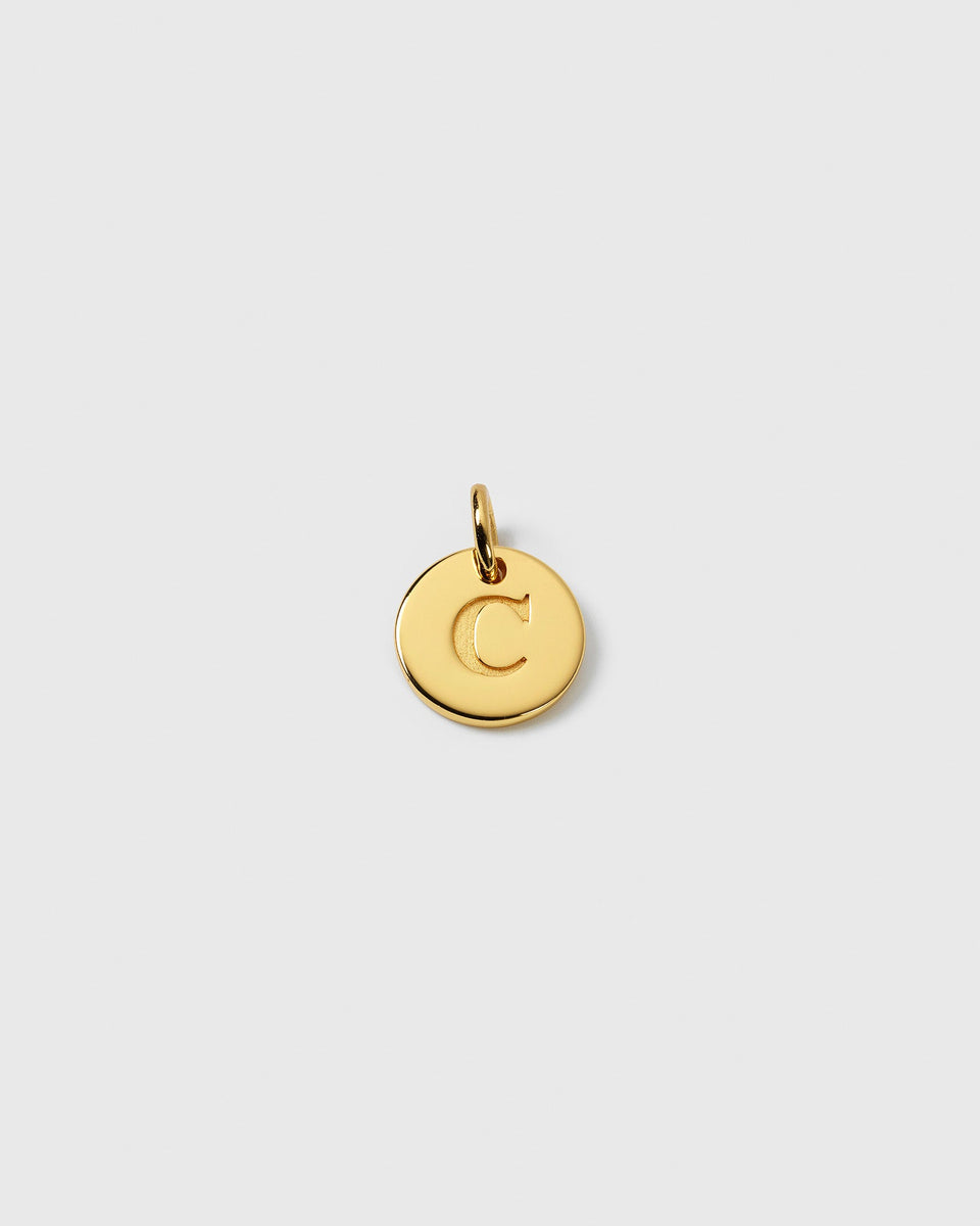 A product shot of the gold Beloved Mini Letter charm, showing the letter C engraved on a round pendant.