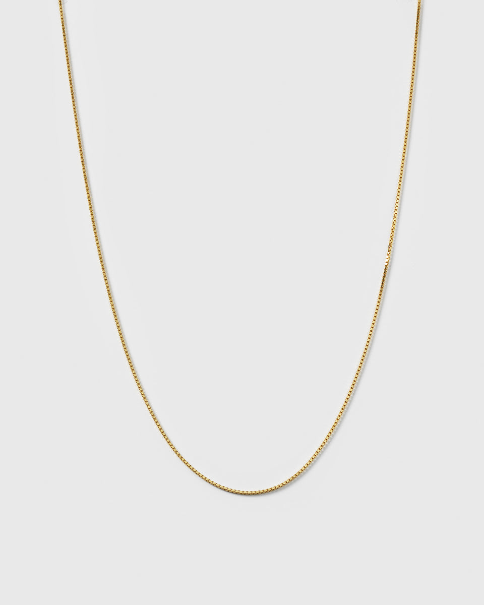 A product shot of the Beloved Long Box Chain in gold, hanging in a U-shape to display its fine box link design.