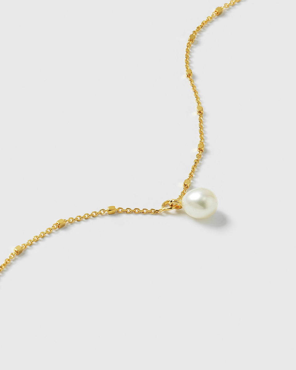 A close-up shot of the Treasure Single Pearl Bracelet in gold, showcasing the unique chain design with tiny shining dots and the single, teardrop-shaped freshwater pearl.