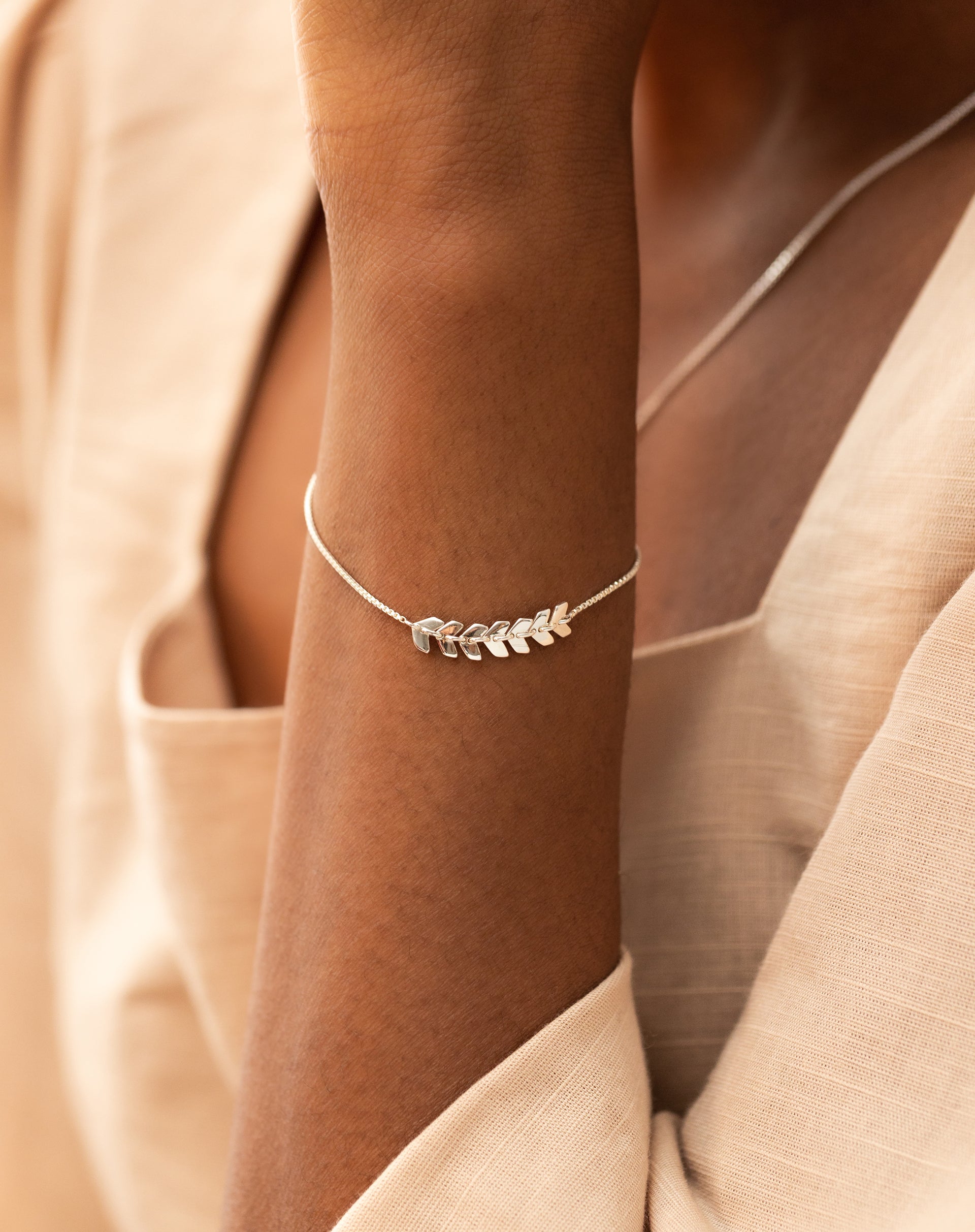 Close-up shot of a model's arm showcasing the Layers Simone Bracelet in silver, which has a delicate leaf-like design.