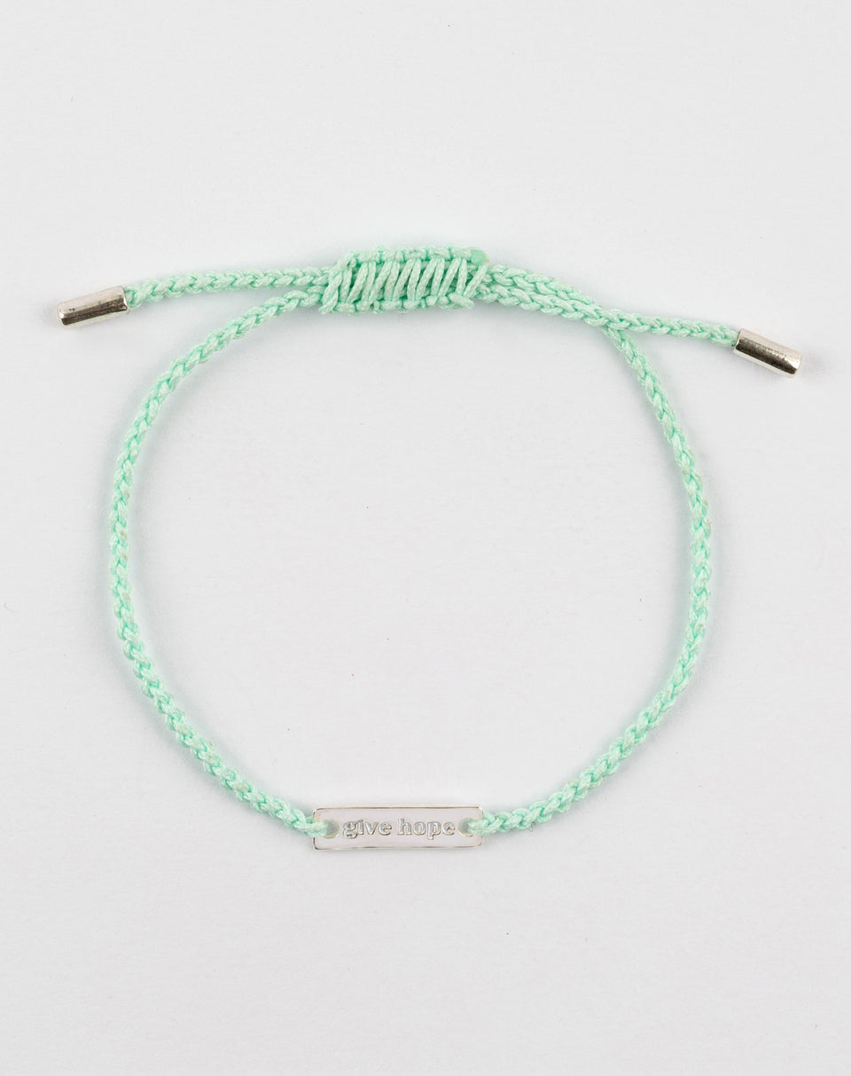 A product shot of the Give Hope bracelet, featuring a mint green braided cord and a silver plaque engraved with the words 'give hope'.