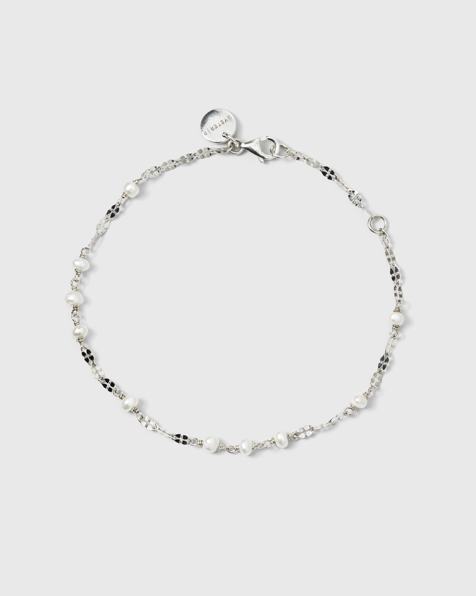 A product shot of the Aurelia Bracelet in silver, laid out in a circle to showcase its delicate chain with unique textured links interspersed with small freshwater pearls.