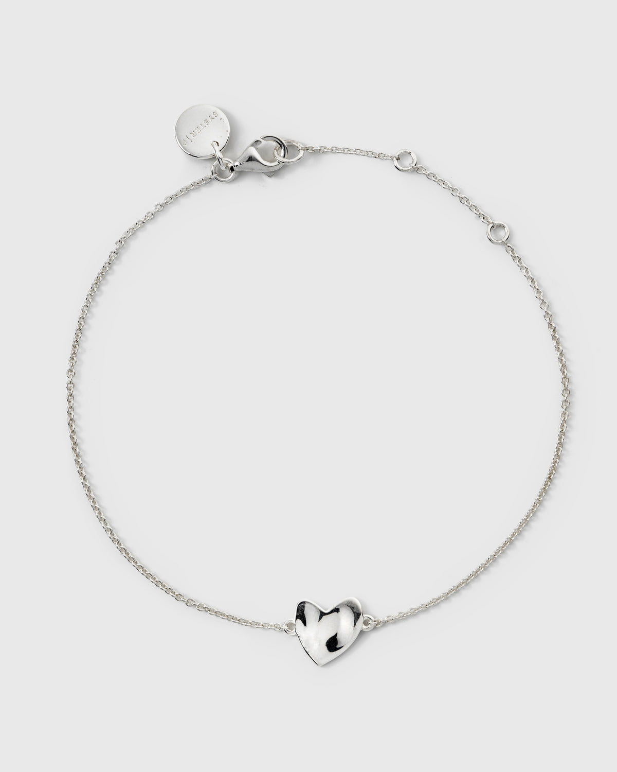 Delicate silver chain bracelet featuring a hammered heart charm.