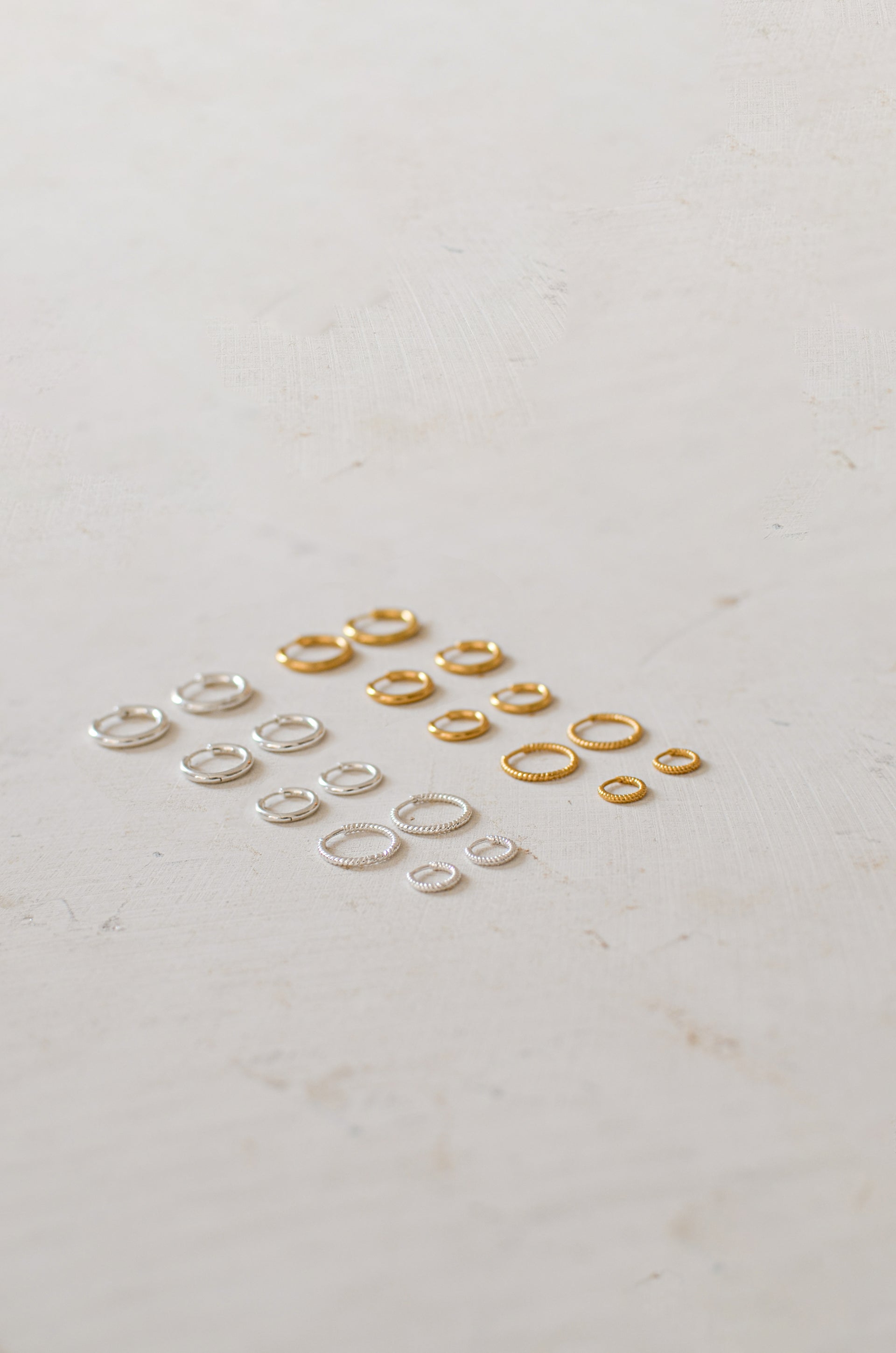 Gold hoops in various sizes next to silver hoops in various sizes