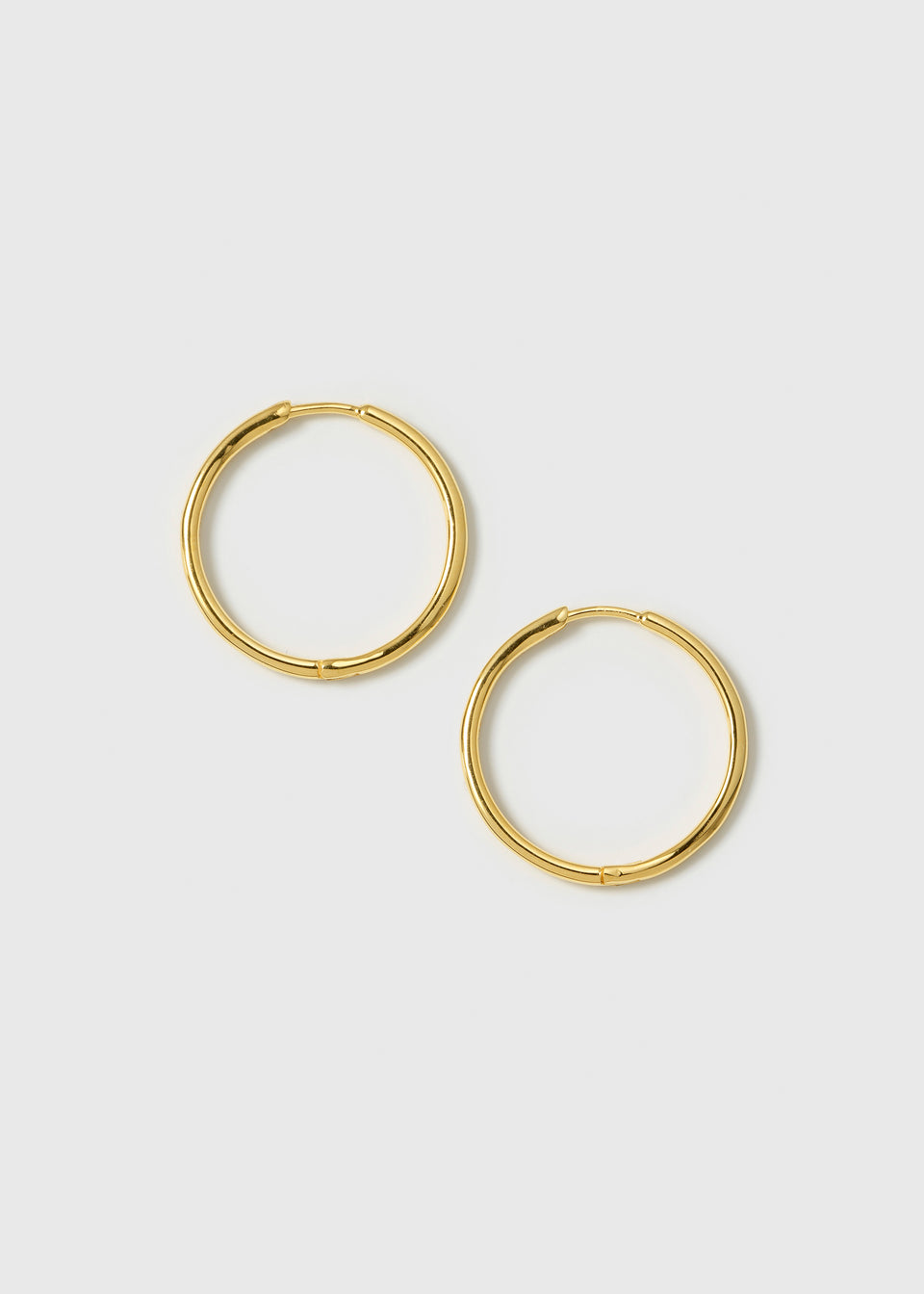A product shot of the Beloved Medium Hoops in gold, laid out flat to showcase their classic, simple design.