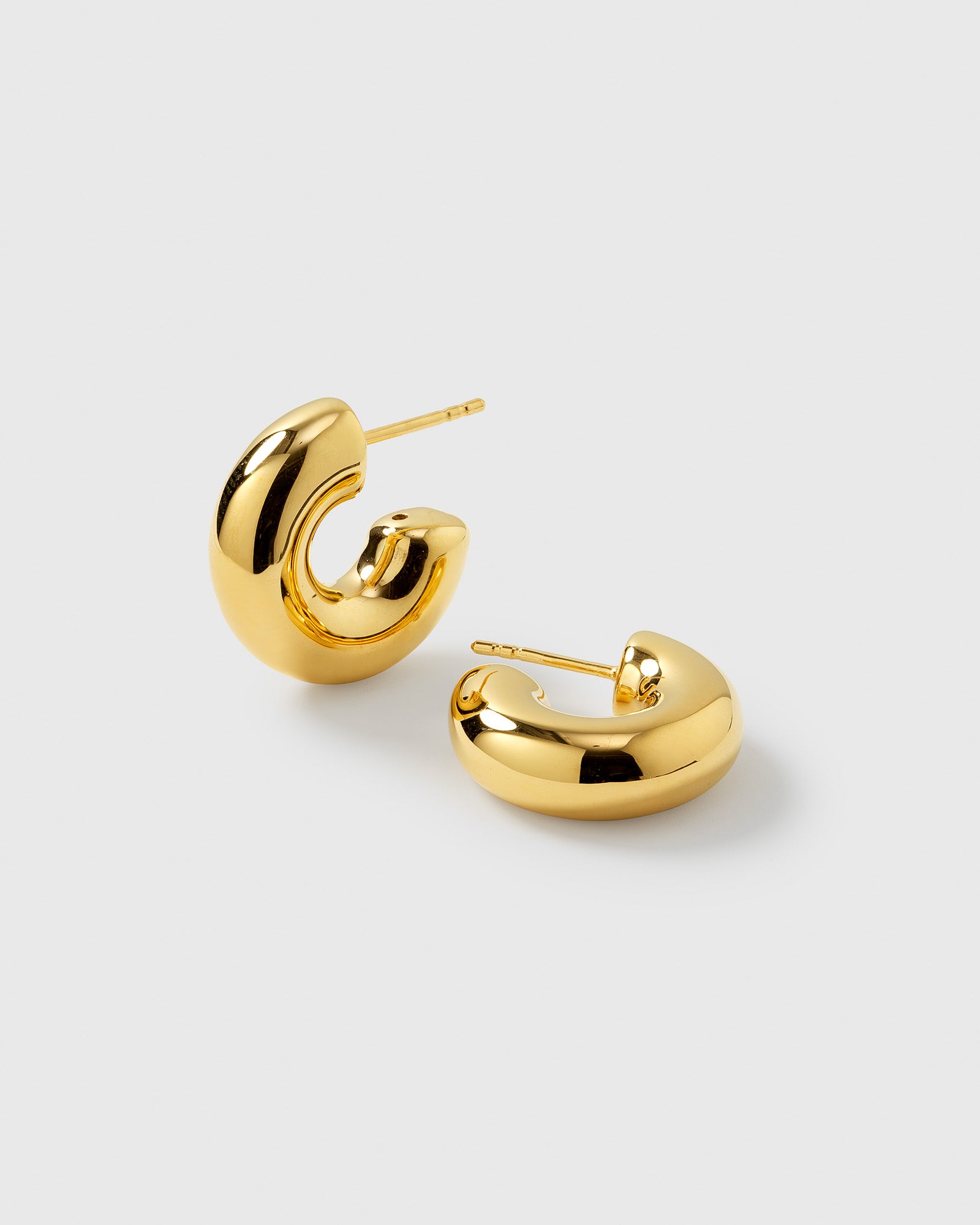 A product shot of the Bolded Little Sis Hoops in gold, showcasing their chunky and polished crescent hoop design.