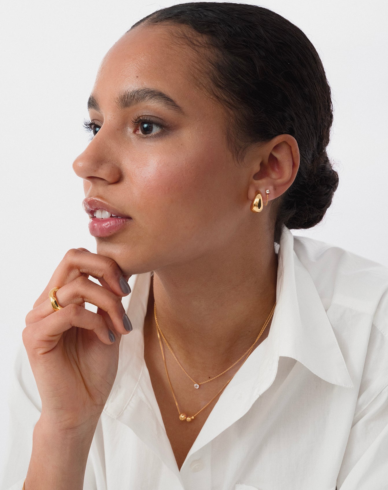 Modell som har på sig Bolded Little Sis Earrings och två halsband.