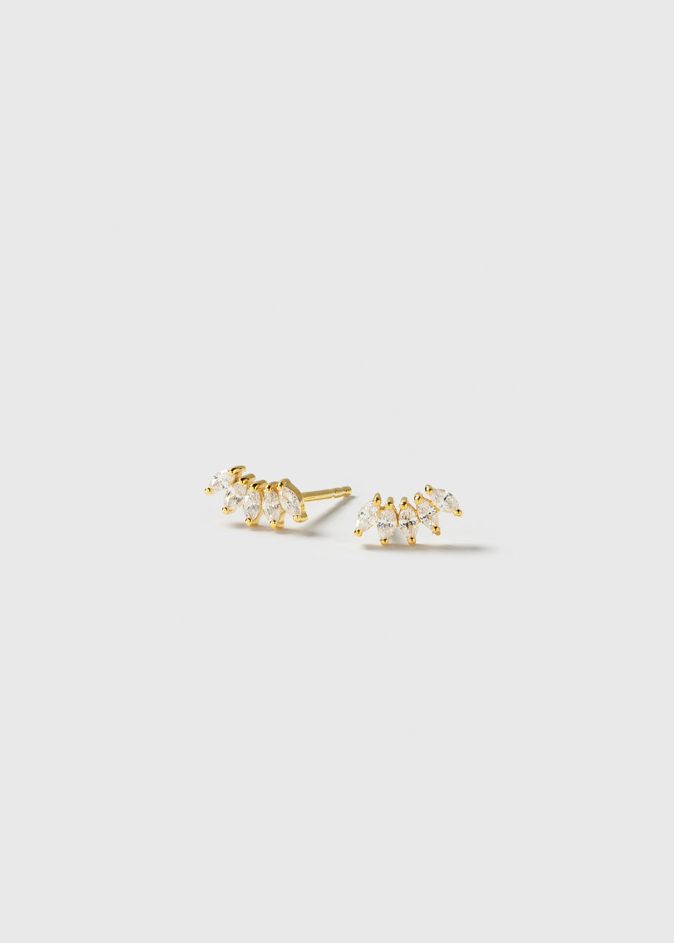 A product shot of the Theodora Earrings in gold, displaying their curved shape adorned with sparkling marquise-cut cubic zirconia stones.