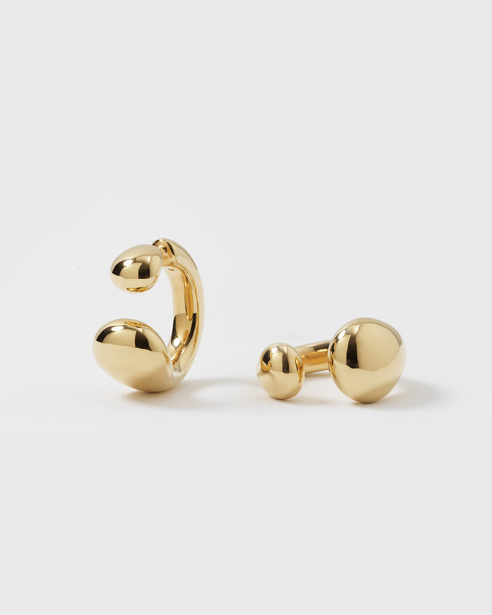 A product shot of the gold Bolded Drops Earrings, illustrating their unique two-part design with the C-shaped hoop and the separate drop-ended post backing.