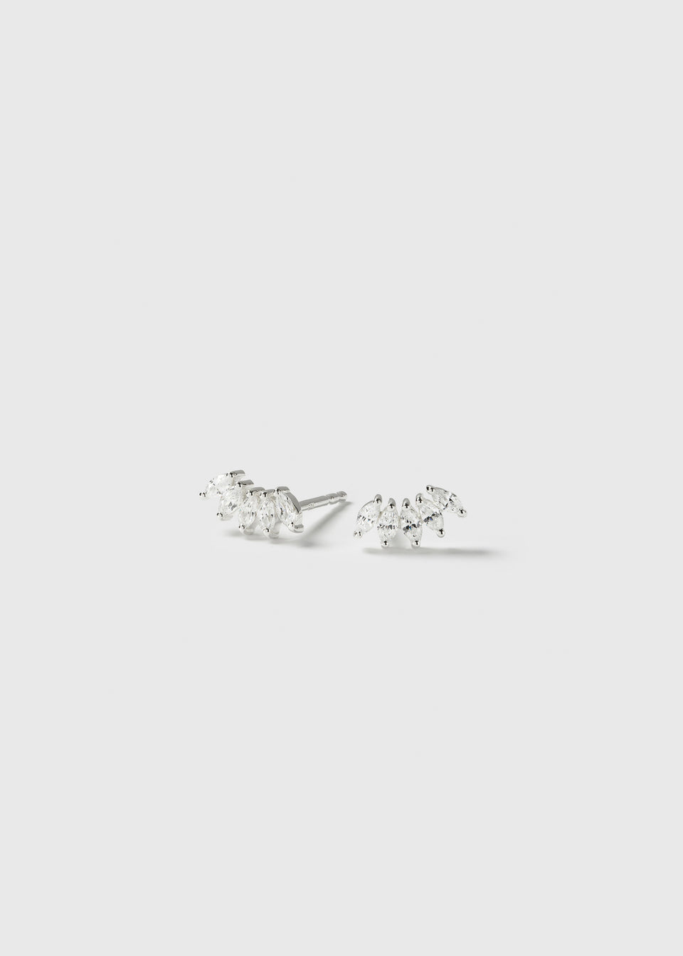 A product shot of the Theodora Earrings in silver, showing the pair of studs with their curved design of sparkling, marquise-cut cubic zirconia stones.