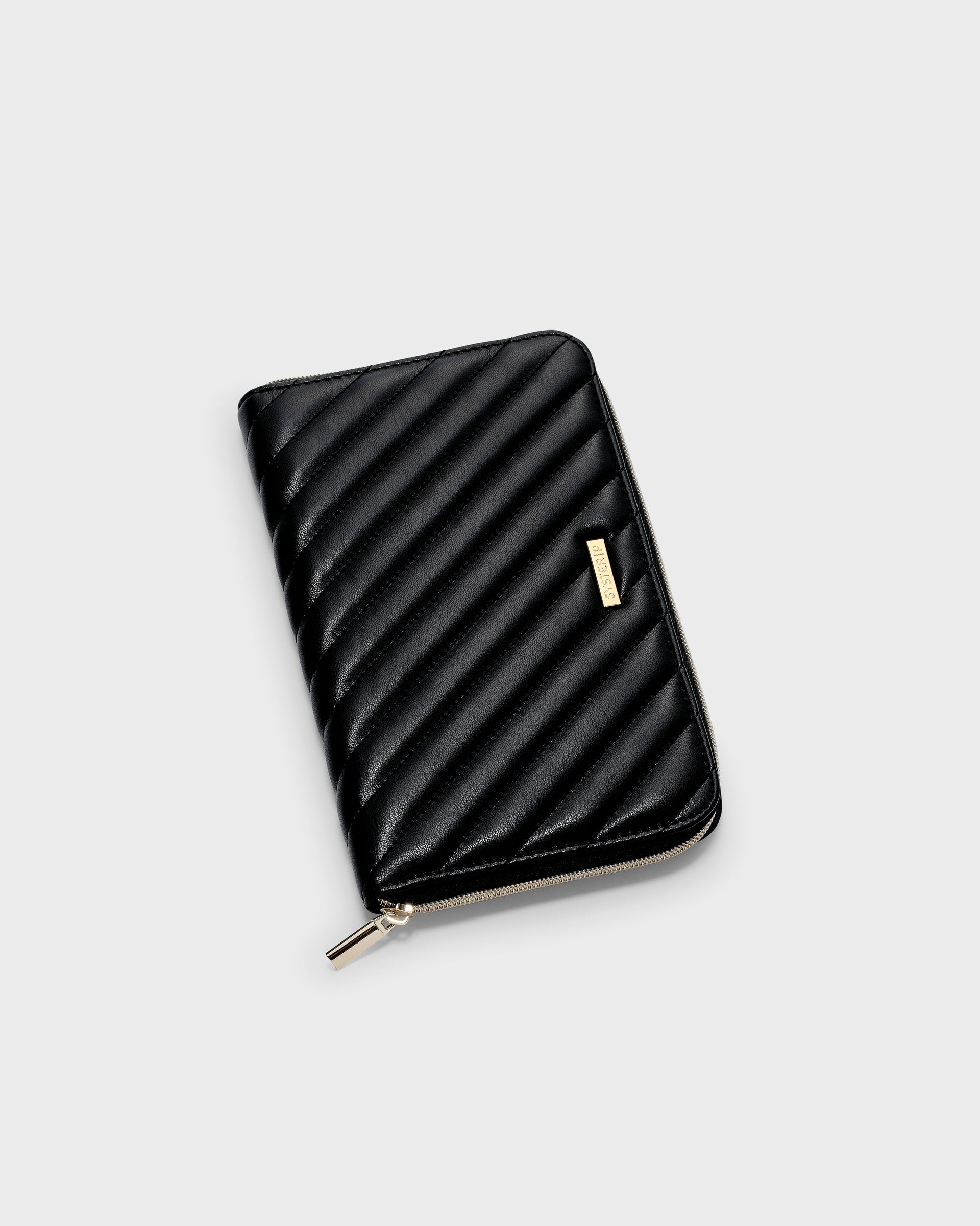 A product shot of the Jewelry Travel Case in black, highlighting its quilted vegan leather exterior, gold-toned zipper, and Syster P logo tag.