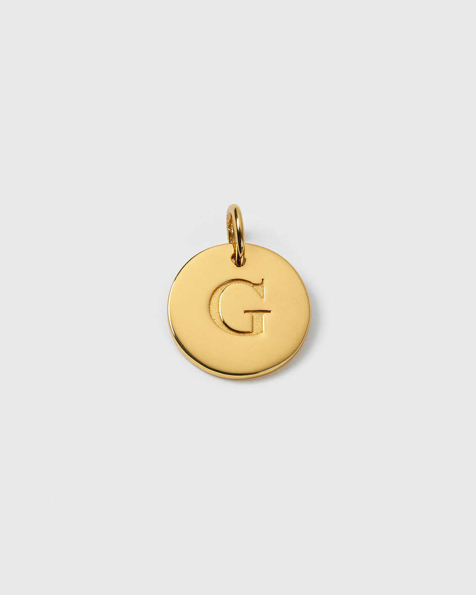 A product shot of the Beloved Big Letter Gold pendant, a circular gold charm with the letter G engraved in the center.