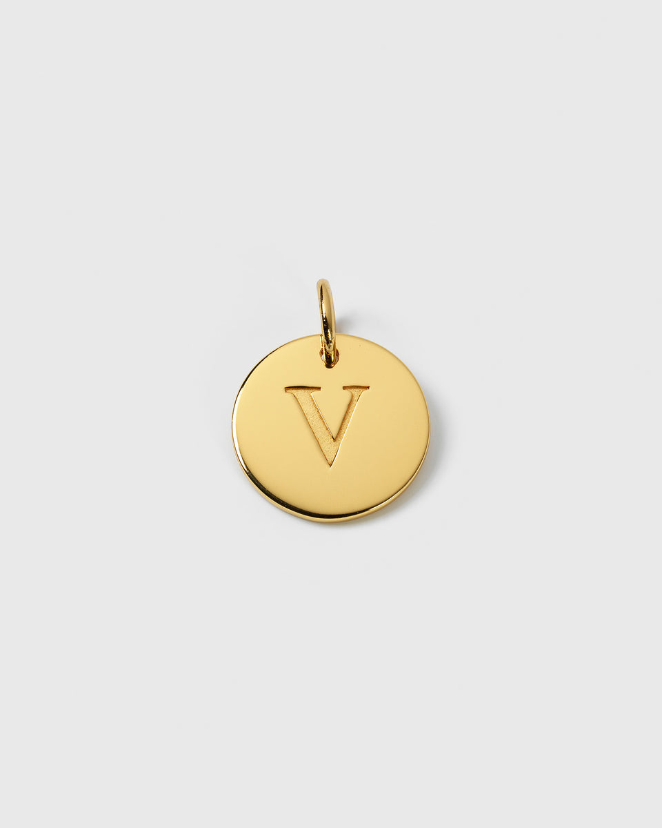 A product shot of the Beloved Big Letter pendant in gold, showing the circular design with the letter 'V' engraved on its surface.