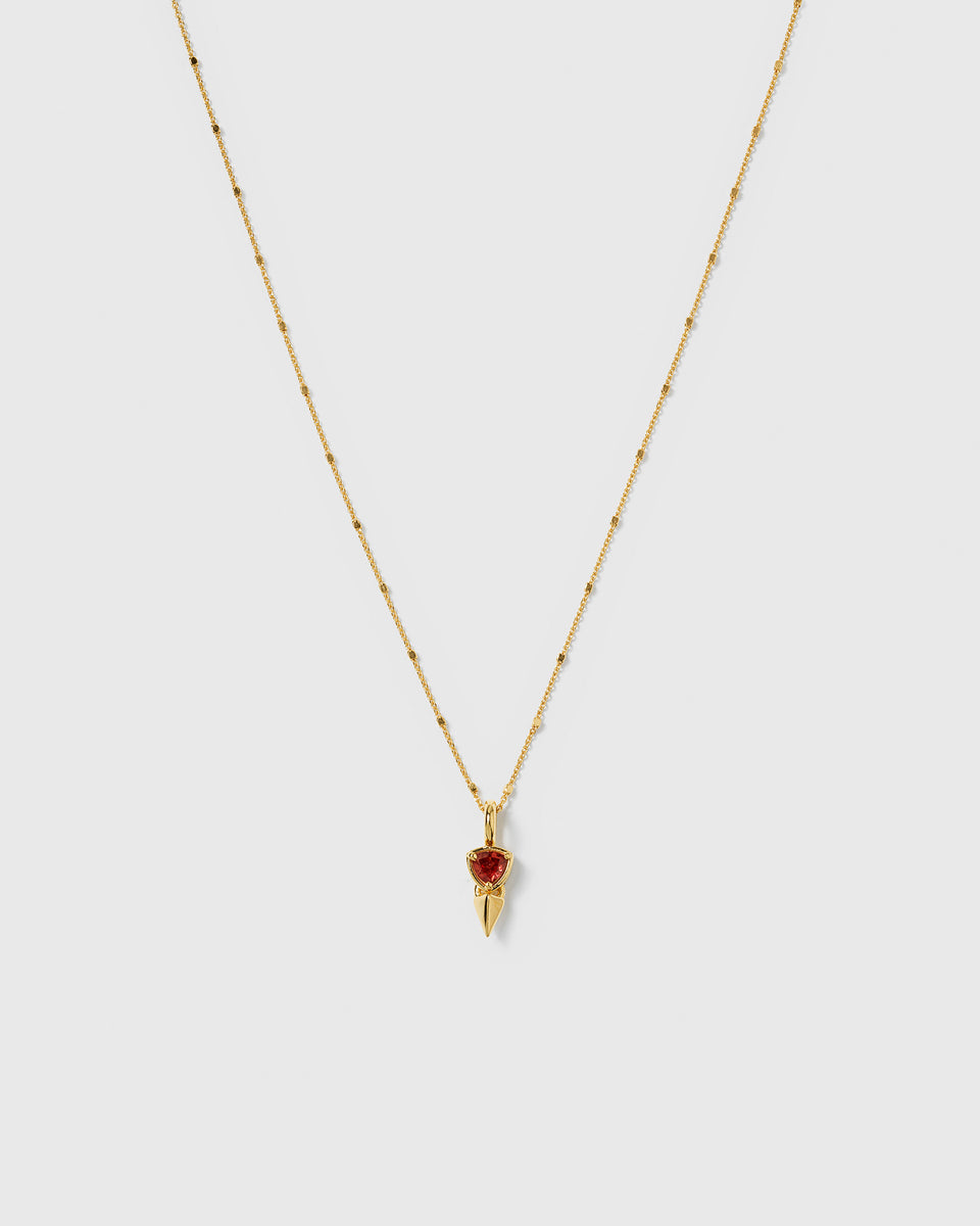 A product shot of the Mrs H Spike Necklace in gold, highlighting its delicate beaded chain and pendant which combines a red garnet stone with a golden spike.