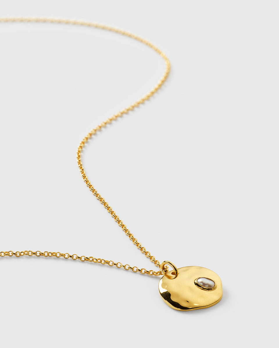 Close-up of the Paxton Necklace in gold, showing the hammered pendant with an inset baroque freshwater pearl on a fine chain.