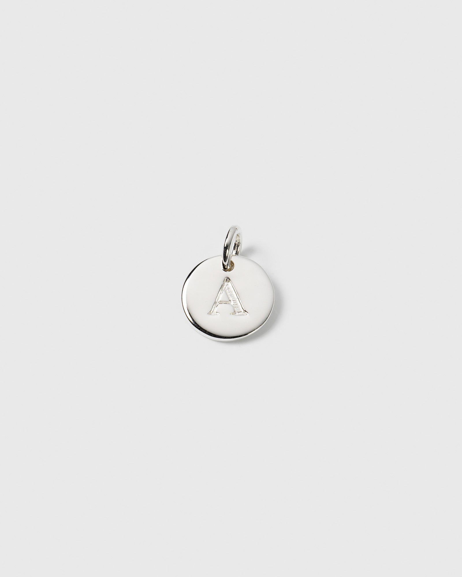 A product shot of the Beloved Mini Letter Silver pendant, featuring a small round charm with the letter 'A' engraved on it.