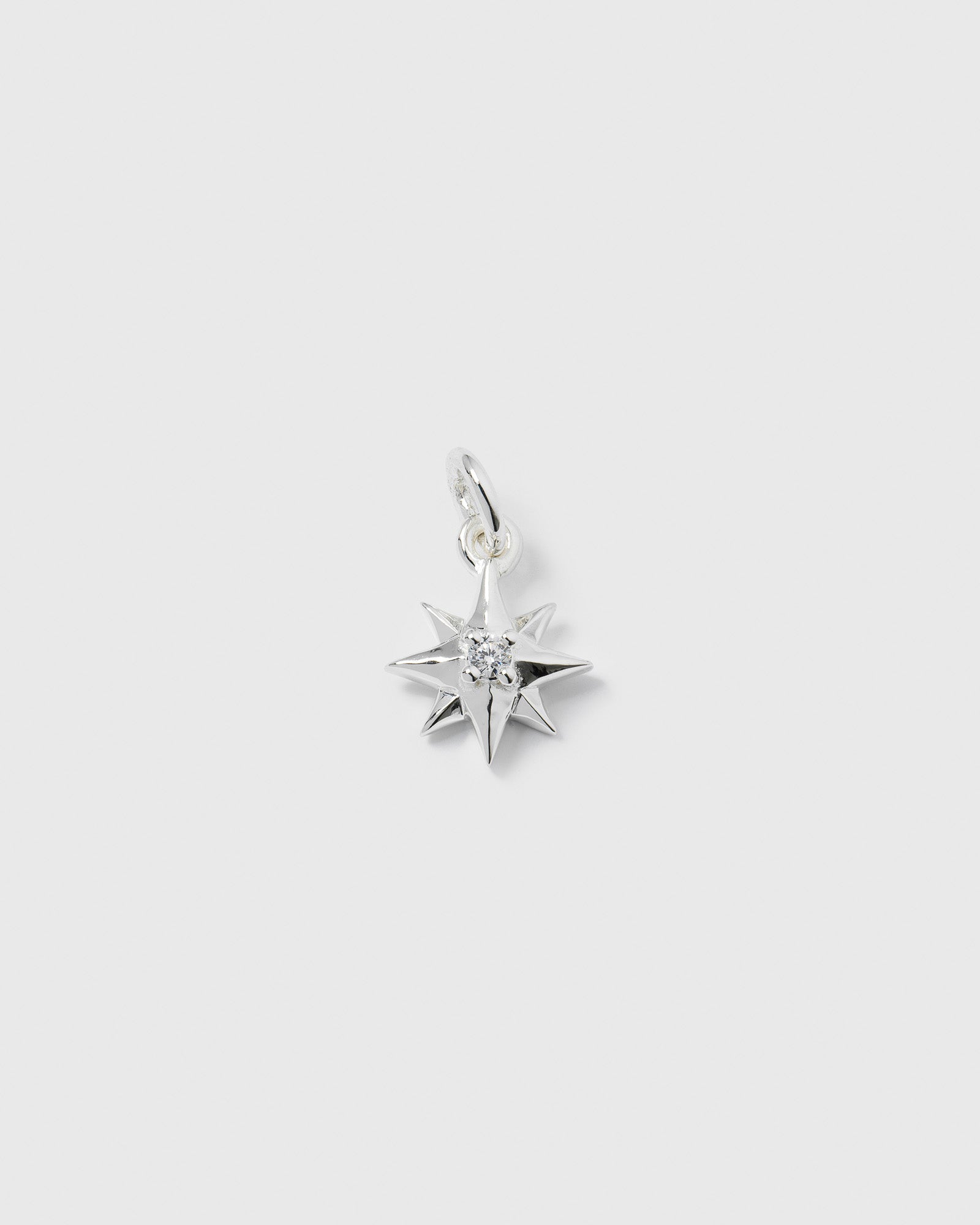 A product shot of the Beloved Compass Star Pendant in silver, featuring a compass star design with a single cubic zirconia set in the center.
