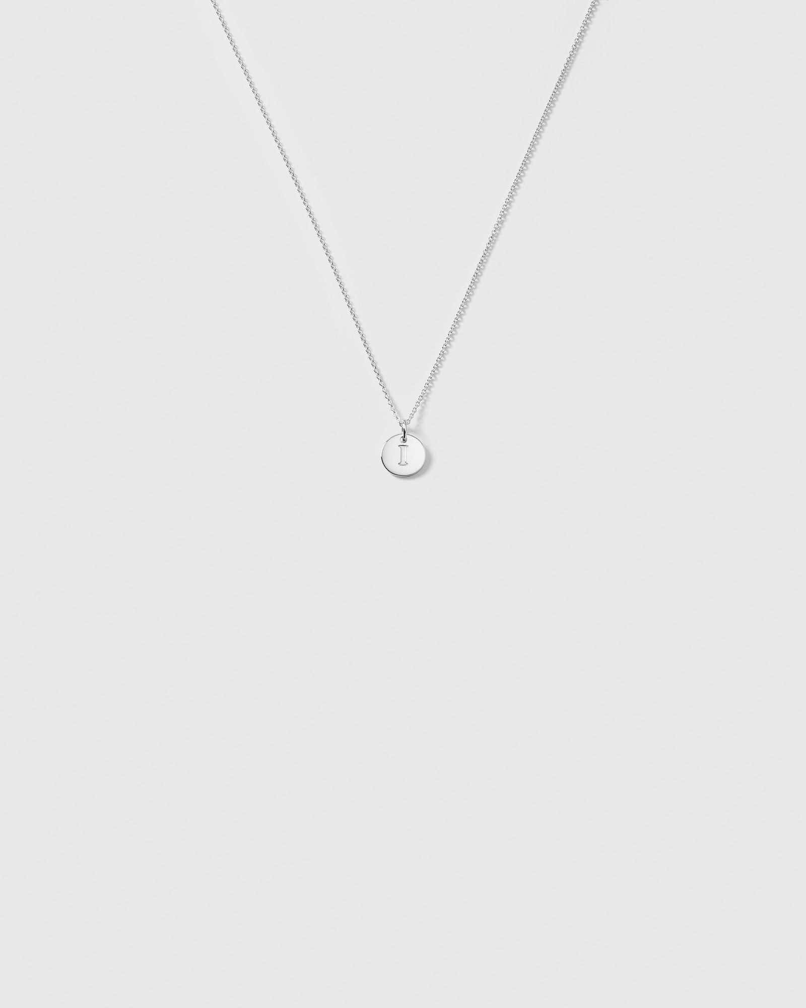 A product shot of the Beloved Baby Chain in silver, featuring the fine anchor chain styled with a small, round 'I' letter pendant.