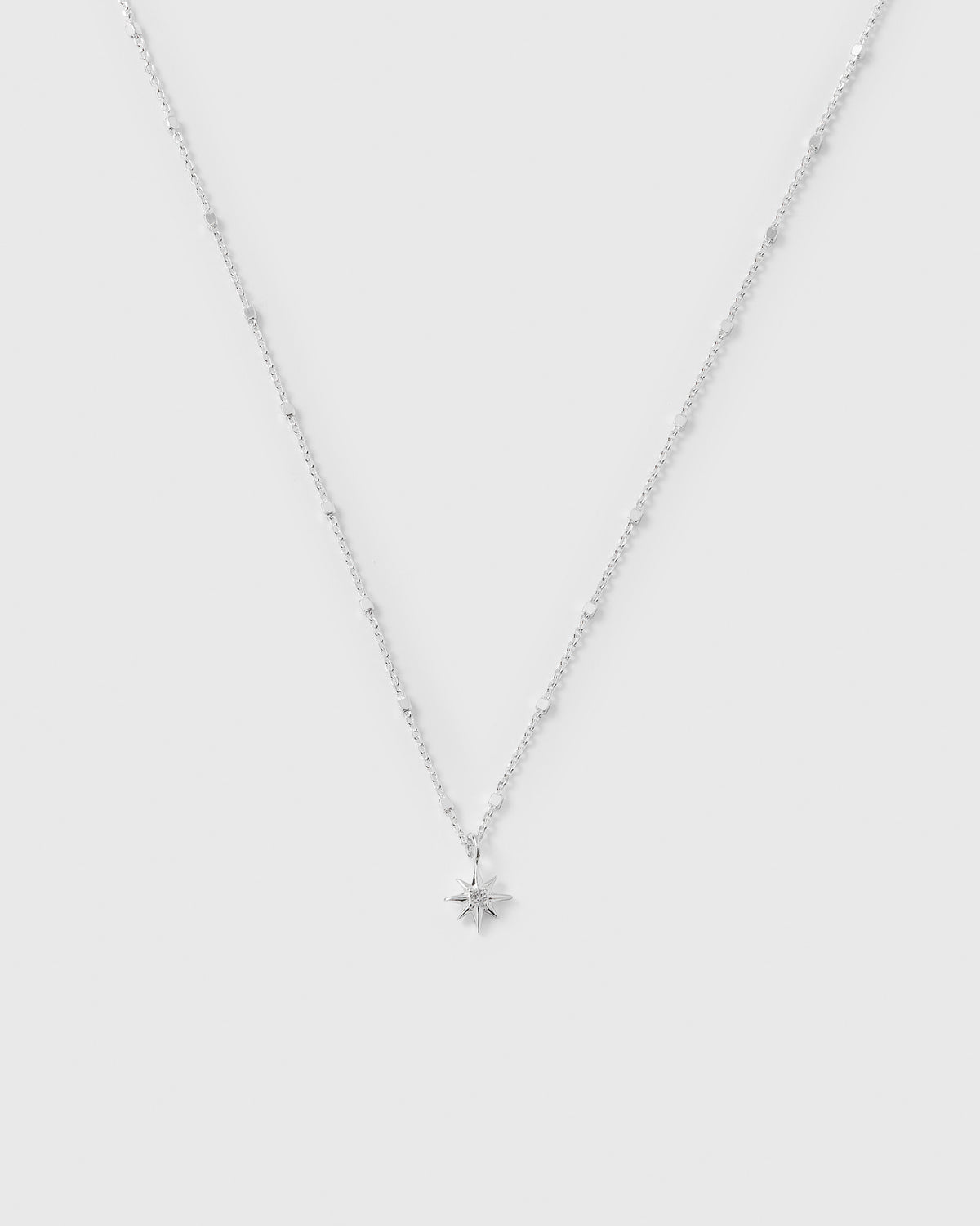 A product shot of the North Star Necklace in silver, featuring a sparkling chain and a small star-shaped pendant set with a facetted crystal.