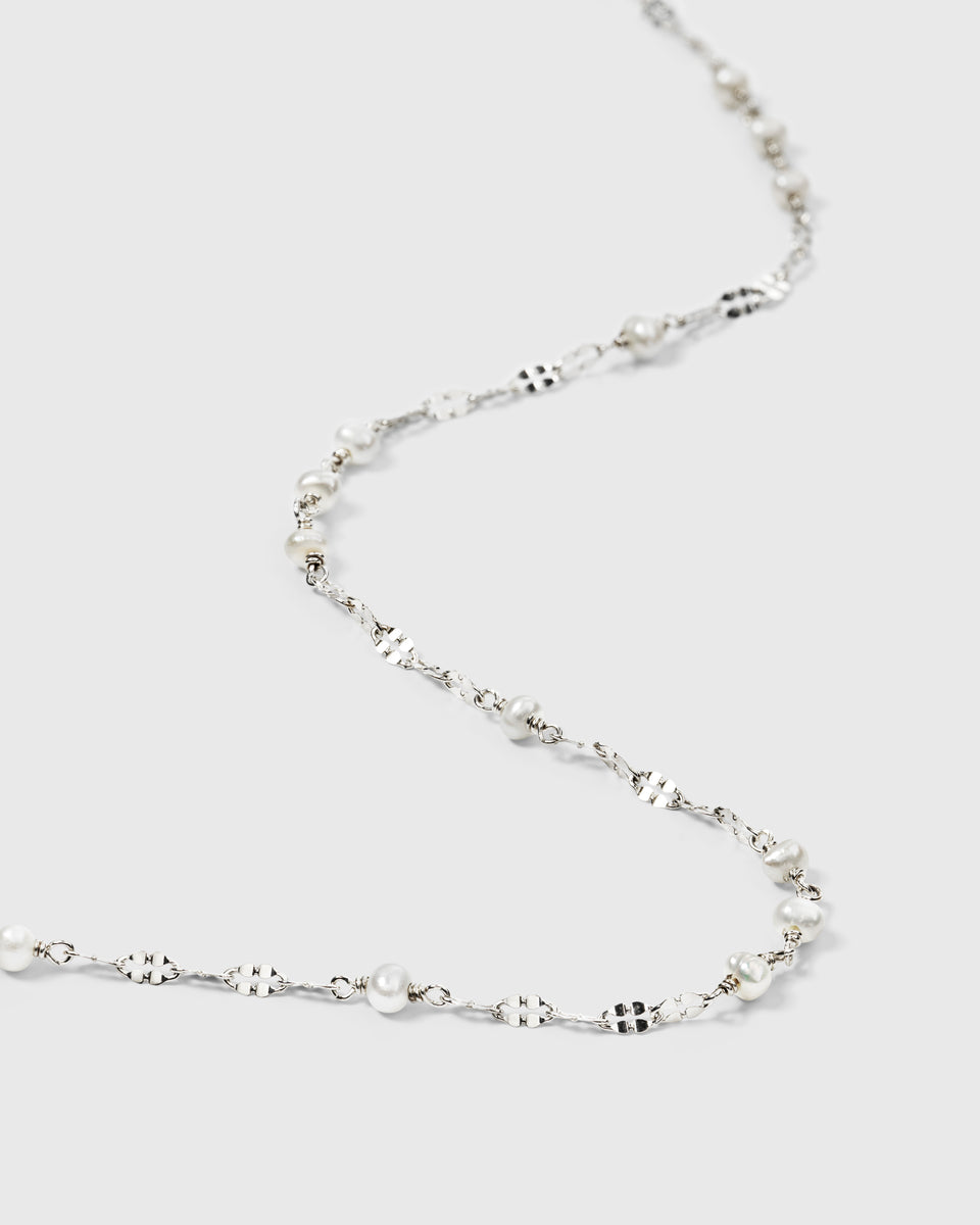 A close-up product shot of the Aurelia Necklace in silver, showcasing its unique patterned chain interspersed with small, lustrous freshwater pearls.