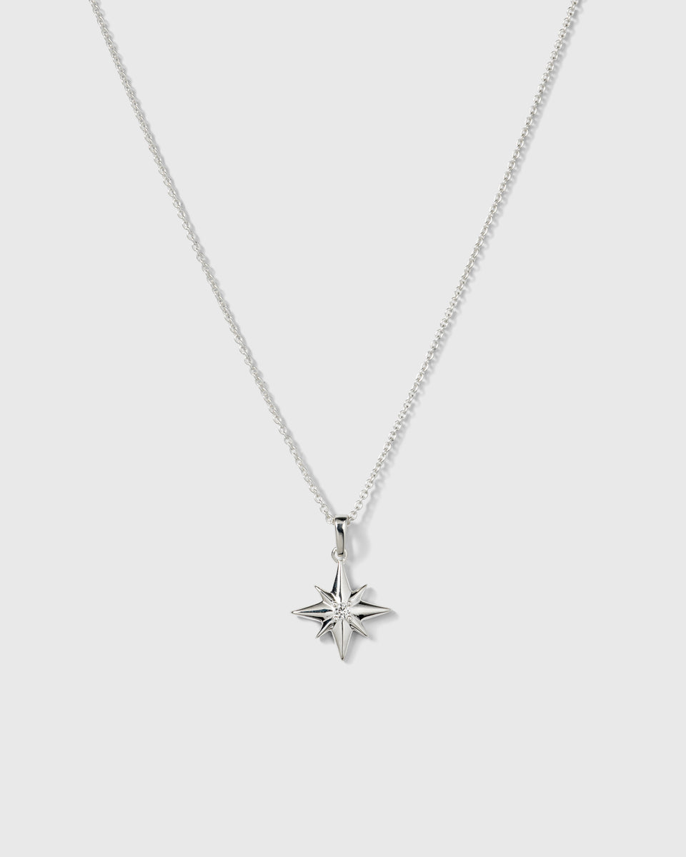 A product shot of the North Star Big Necklace in silver, featuring a delicate chain and a pendant shaped like an eight-pointed star with a crystal at its center.