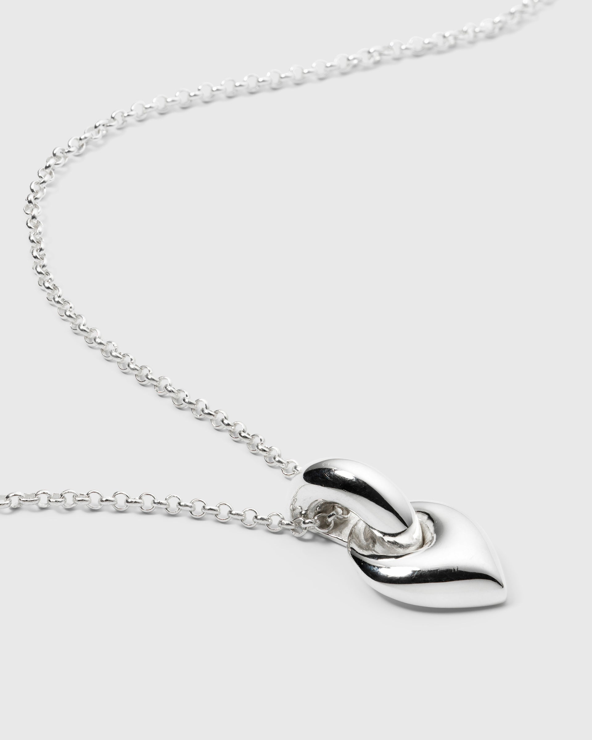 A close-up shot of the Melinda Long Necklace in silver, showcasing its chunky leaf-shaped pendant and classic rolo chain.