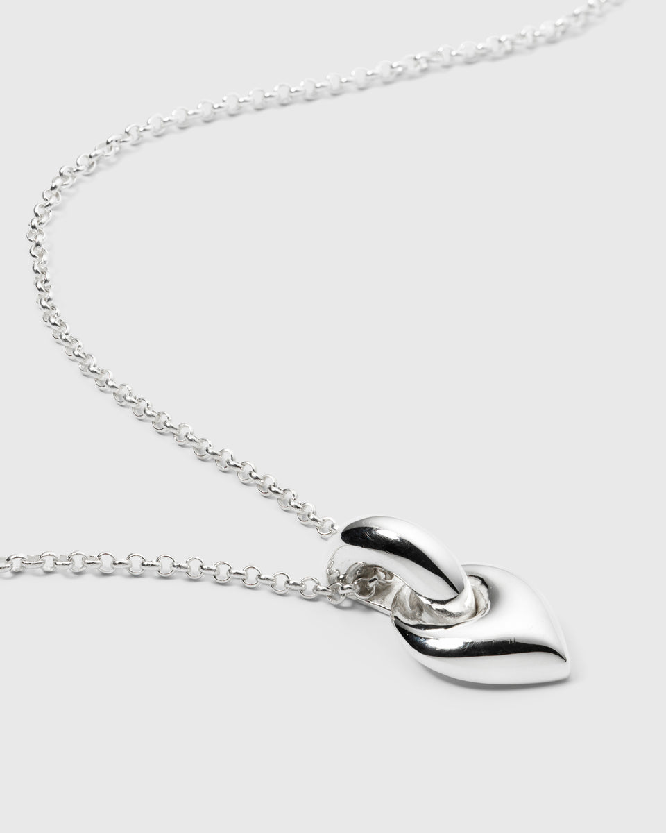 A close-up shot of the Melinda Long Necklace in silver, showcasing its chunky leaf-shaped pendant and classic rolo chain.