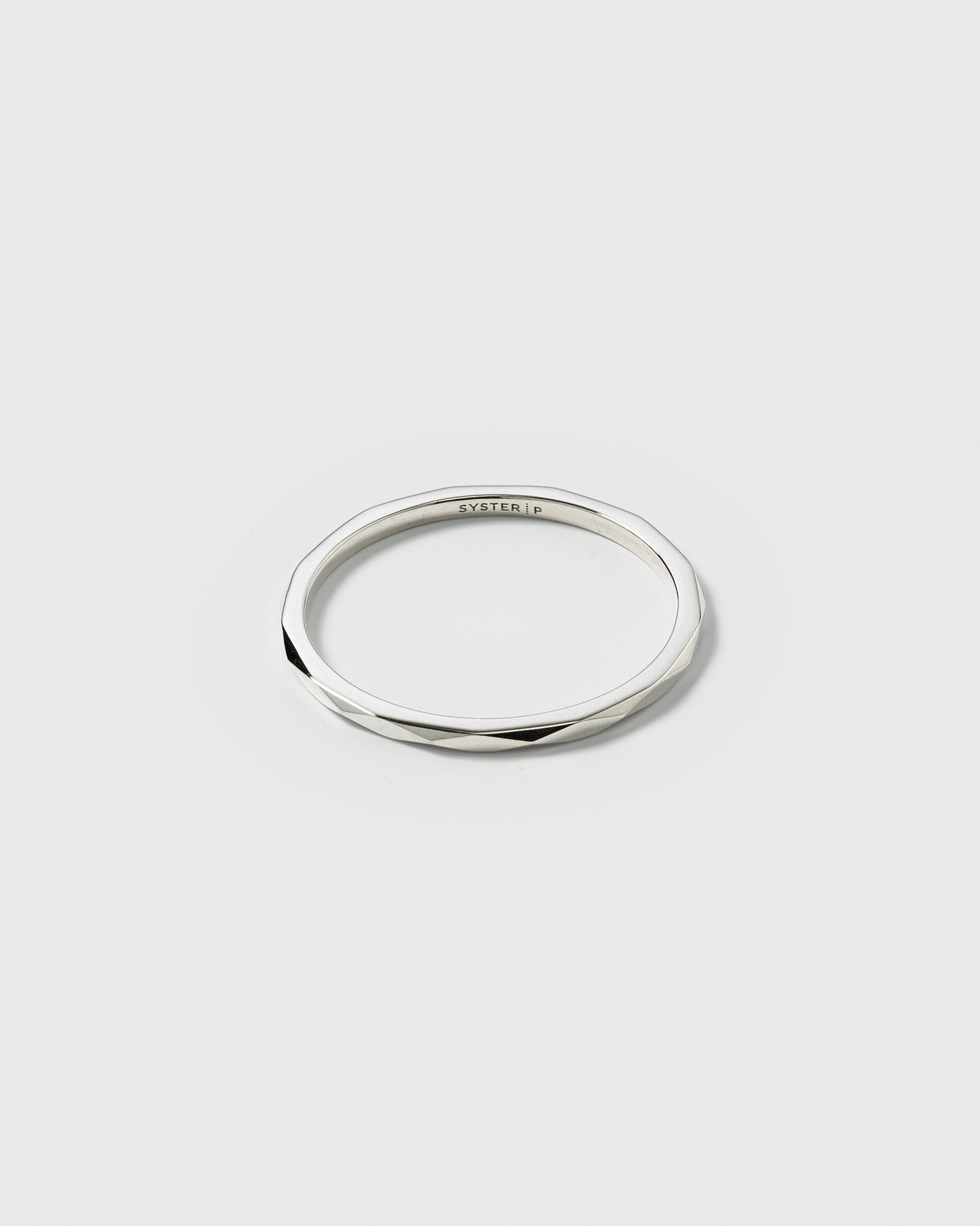 A product shot of the Tiny Ultrathin Ring in silver, showcasing its thin band with a faceted, structured surface.