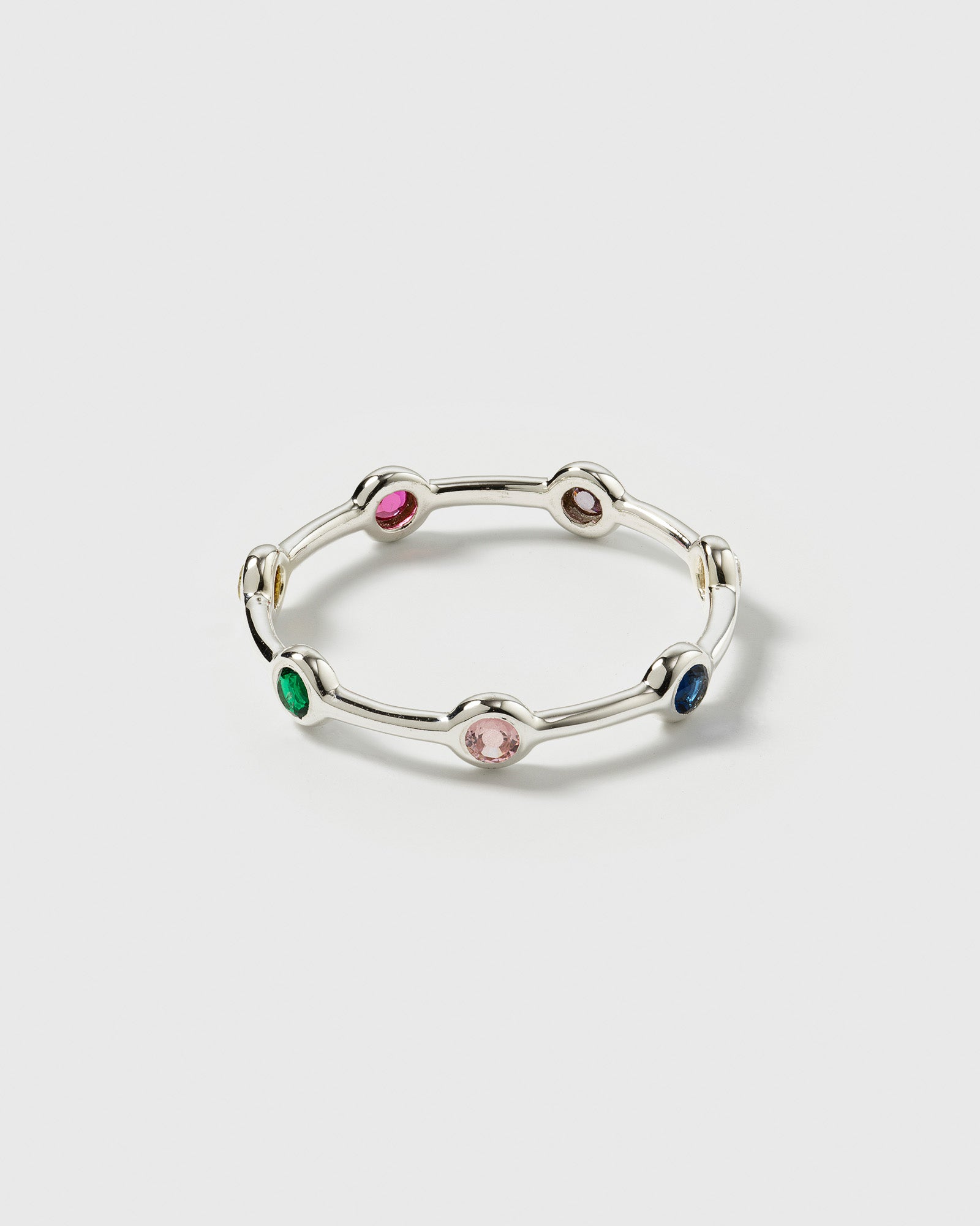 A product shot of the Treasure Shimmer Ring in silver, showcasing its delicate band design set with various colorful, faceted zirconias.