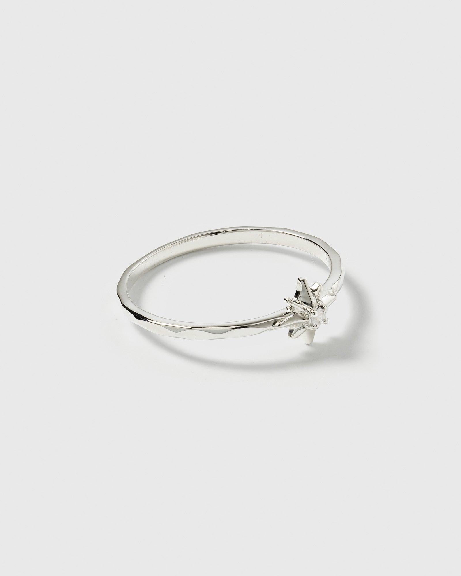 A product shot of the North Star Ring in silver, featuring a thin band decorated with a star and a faceted crystal.