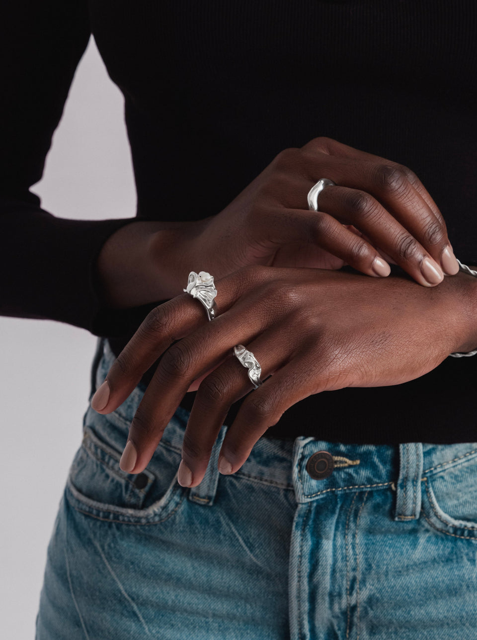 A model shot showcasing the Moulded Big Ring in silver, with its organic shape and freshwater pearl, worn alongside another textured silver ring and a simple silver dome ring.