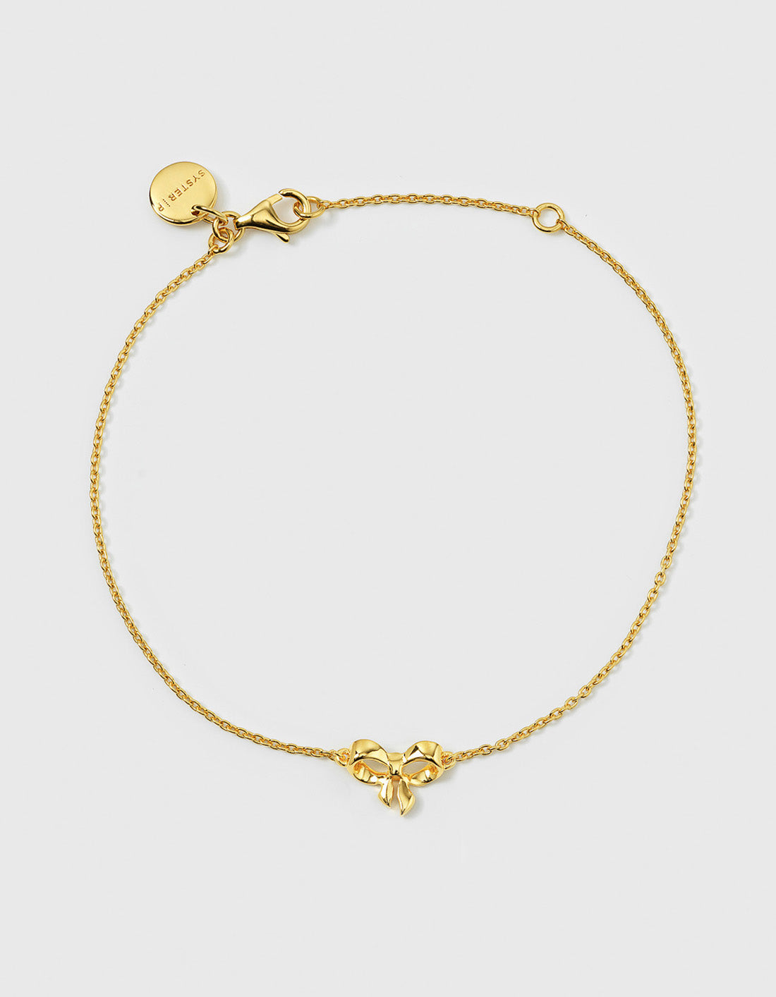 A product shot of the Rosie Mini Bracelet Gold, laid out in a circle to show its delicate, sparkling chain and central bow-shaped pendant.