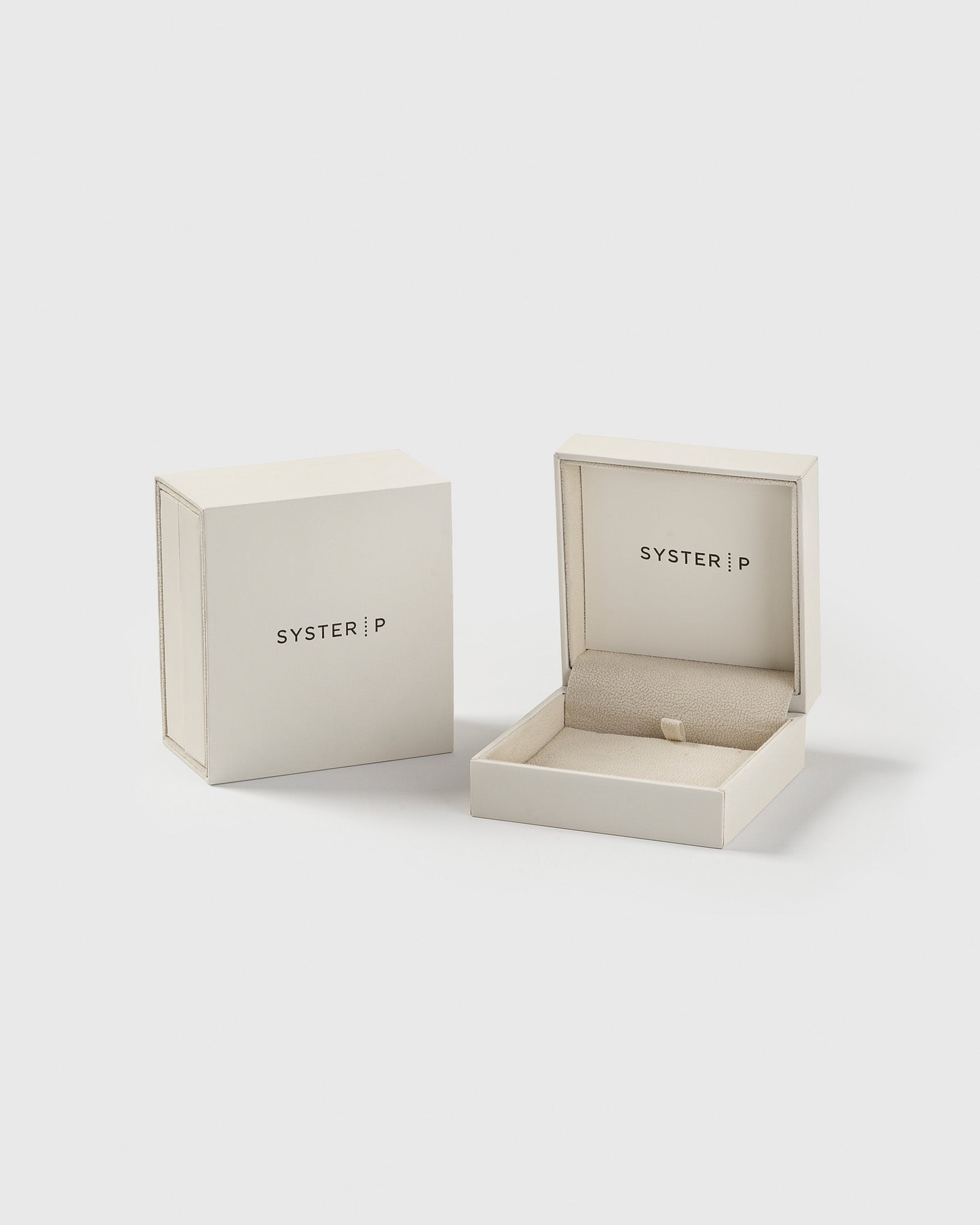 A product shot of the white Syster P jewelry box, shown open to reveal its padded interior alongside the closed box.