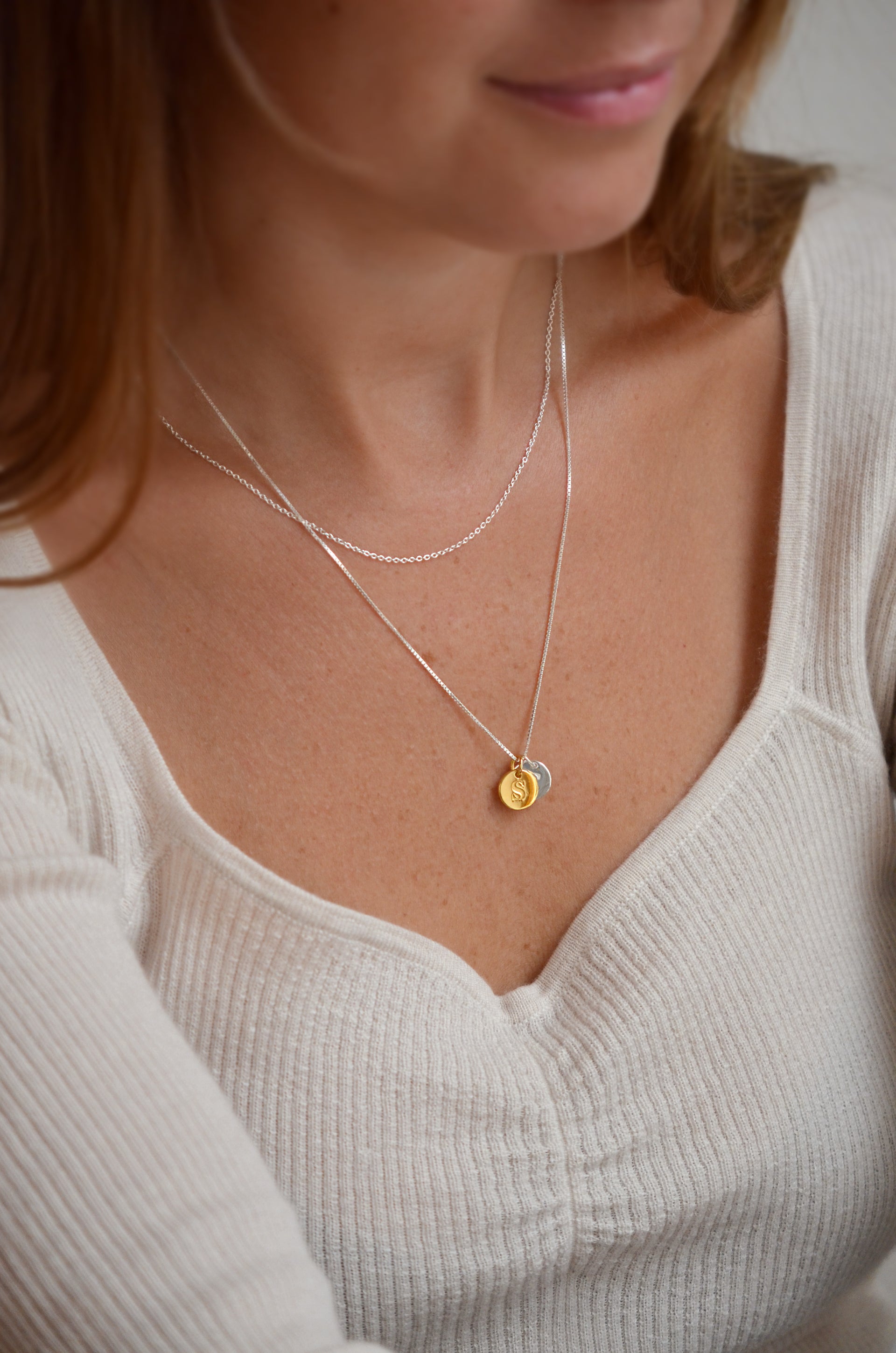 One short silver chain and one medium long silver chain with a gold mini letter and a silver mini letter