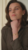 A gold bracelet with a layered design, styled with a thin gold beaded bracelet and pearl earring. 